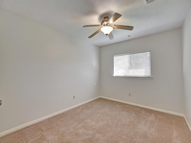 spare room featuring a ceiling fan, light carpet, a textured ceiling, and baseboards