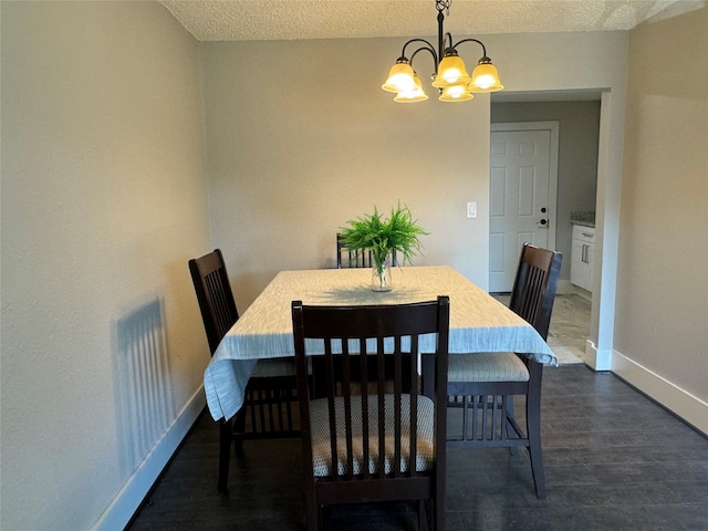 dining space with a notable chandelier, dark wood-type flooring, and a textured ceiling