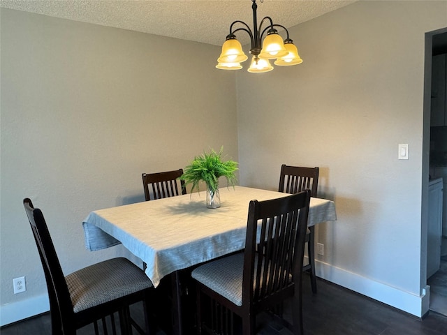 dining room with dark hardwood / wood-style floors, an inviting chandelier, and a textured ceiling