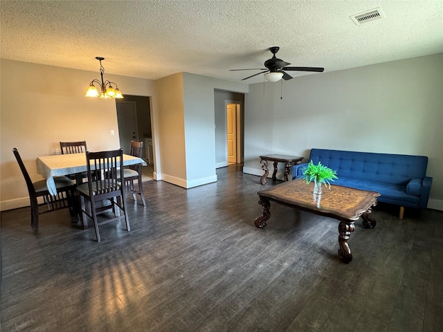 living room with dark wood-type flooring, ceiling fan with notable chandelier, and a textured ceiling