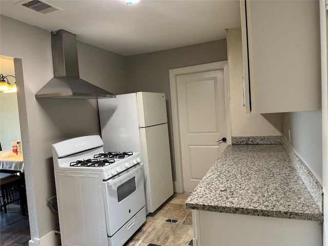 kitchen featuring light stone counters, wall chimney range hood, white cabinetry, and white range with gas stovetop