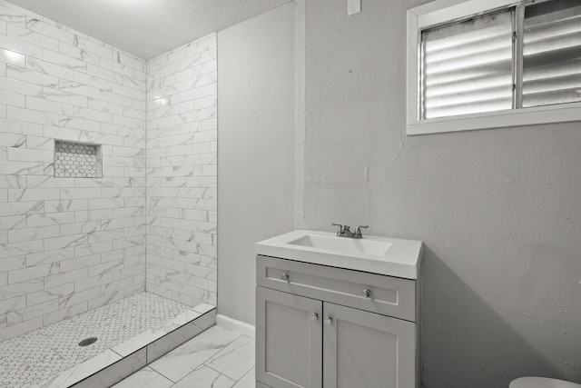 bathroom with tiled shower, vanity, and a textured ceiling