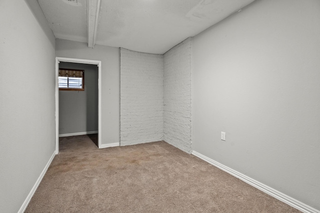 carpeted empty room featuring beamed ceiling