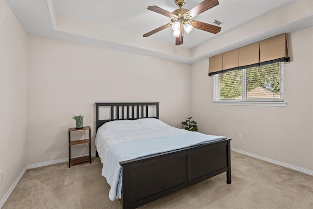 carpeted bedroom featuring a tray ceiling and ceiling fan