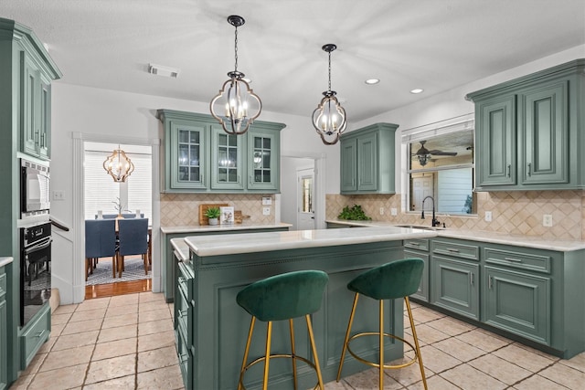 kitchen with built in microwave, sink, black oven, and green cabinets