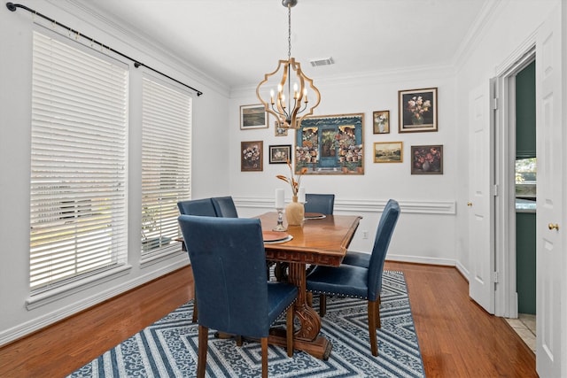 dining area featuring an inviting chandelier, crown molding, wood-type flooring, and a healthy amount of sunlight