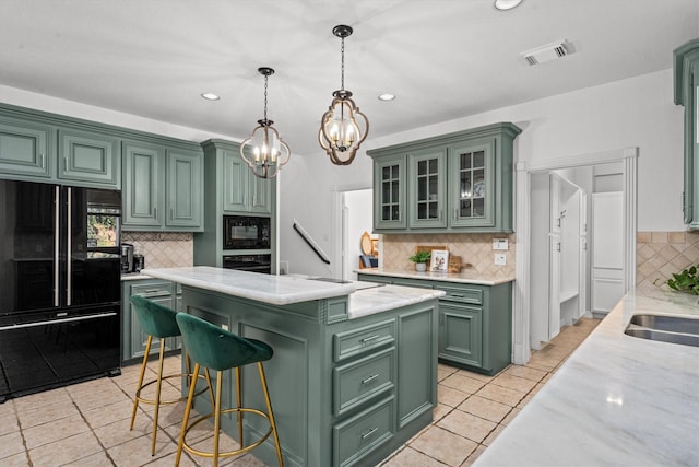 kitchen featuring pendant lighting, black appliances, a center island, light tile patterned floors, and green cabinetry