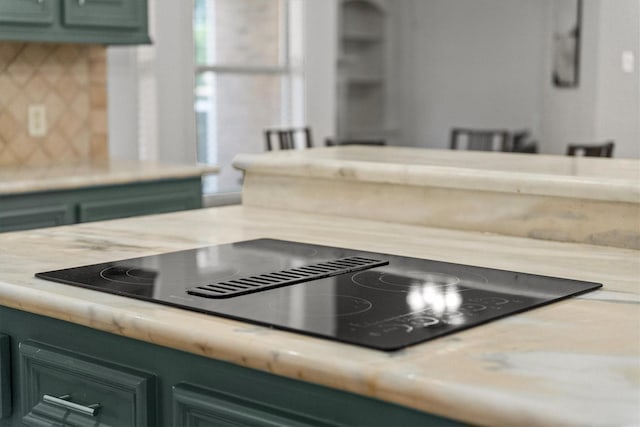 details featuring black electric stovetop, backsplash, and green cabinets