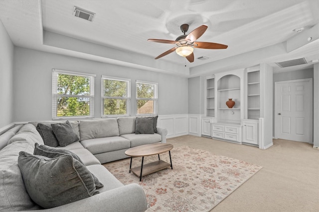 carpeted living room featuring ceiling fan and a tray ceiling