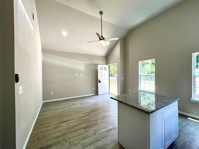 kitchen featuring dark stone counters, open floor plan, white cabinets, and light wood-style flooring