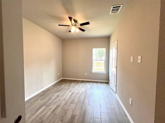 spare room featuring ceiling fan, wood finished floors, visible vents, and baseboards