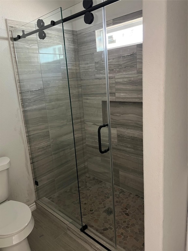 bathroom with a shower with door and toilet