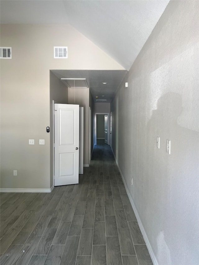 hallway with dark wood-style floors, visible vents, and attic access