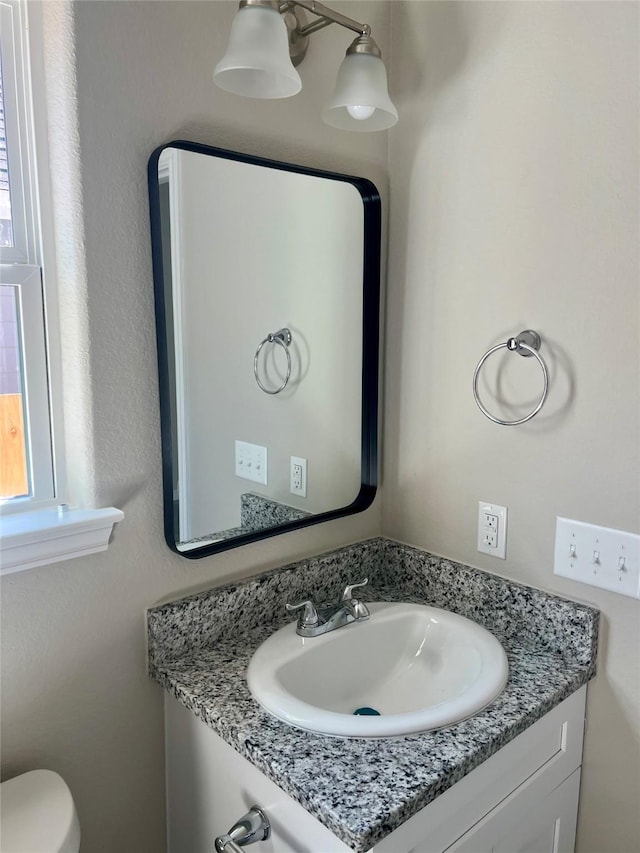 bathroom with vanity, a healthy amount of sunlight, and toilet