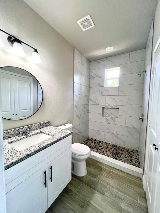 full bathroom featuring visible vents, a shower stall, toilet, and vanity