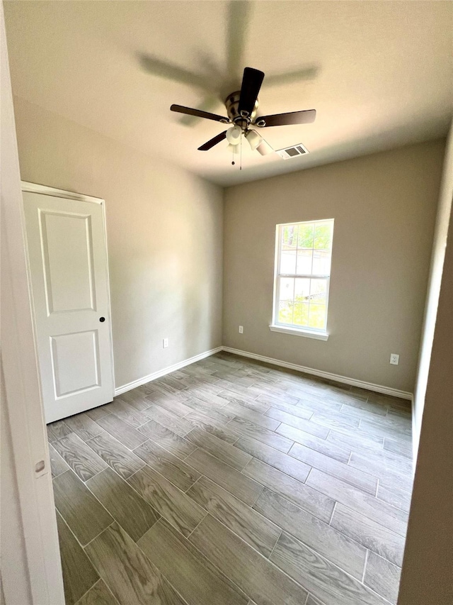 unfurnished room featuring ceiling fan, wood finished floors, visible vents, and baseboards