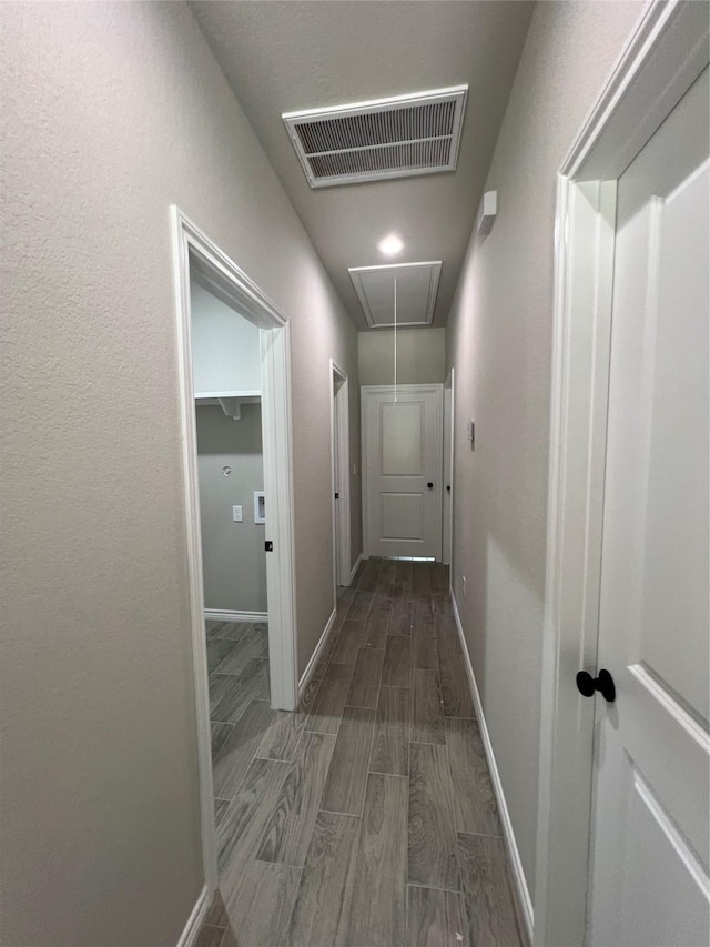 hallway with baseboards, wood tiled floor, visible vents, and attic access