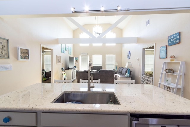 kitchen featuring high vaulted ceiling, sink, beverage cooler, ceiling fan, and light stone countertops