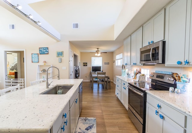 kitchen featuring sink, appliances with stainless steel finishes, independent washer and dryer, a kitchen island with sink, and white cabinets