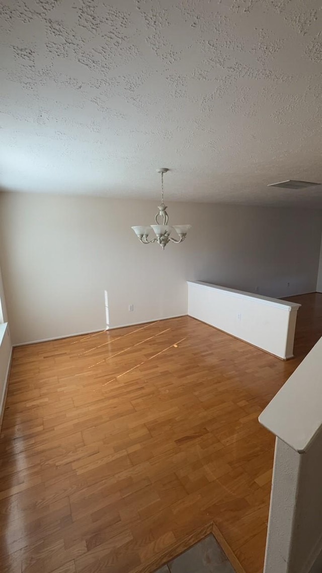 interior space featuring an inviting chandelier, hardwood / wood-style floors, and a textured ceiling