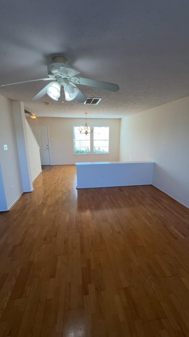 empty room with wood-type flooring and ceiling fan with notable chandelier