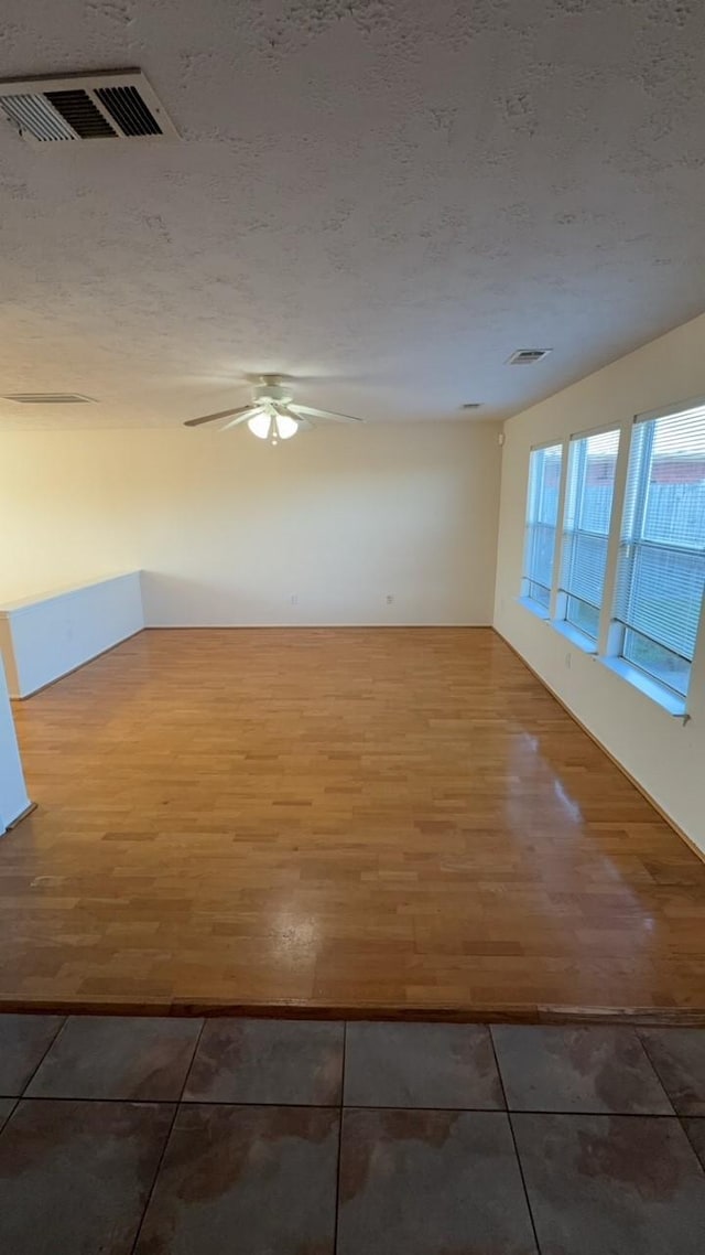 unfurnished room with ceiling fan, hardwood / wood-style flooring, and a textured ceiling