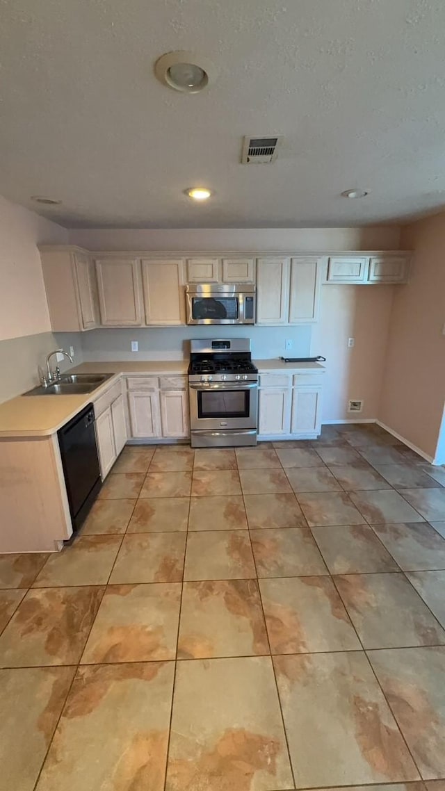 kitchen with white cabinetry, appliances with stainless steel finishes, sink, and light tile patterned floors