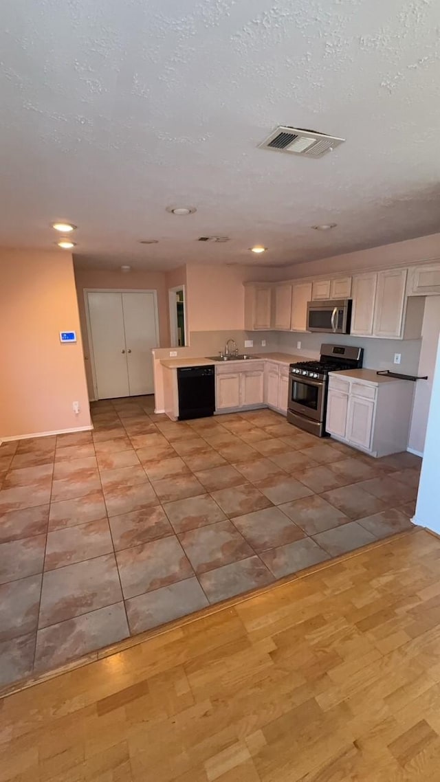 kitchen featuring stainless steel appliances, white cabinets, and a textured ceiling