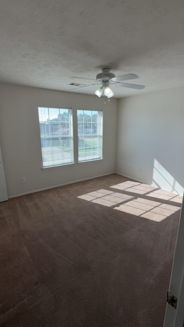 empty room featuring ceiling fan, light colored carpet, and a textured ceiling