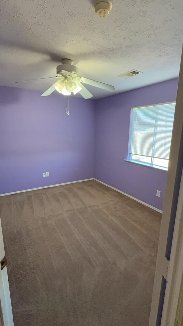 empty room with ceiling fan, carpet floors, and a textured ceiling