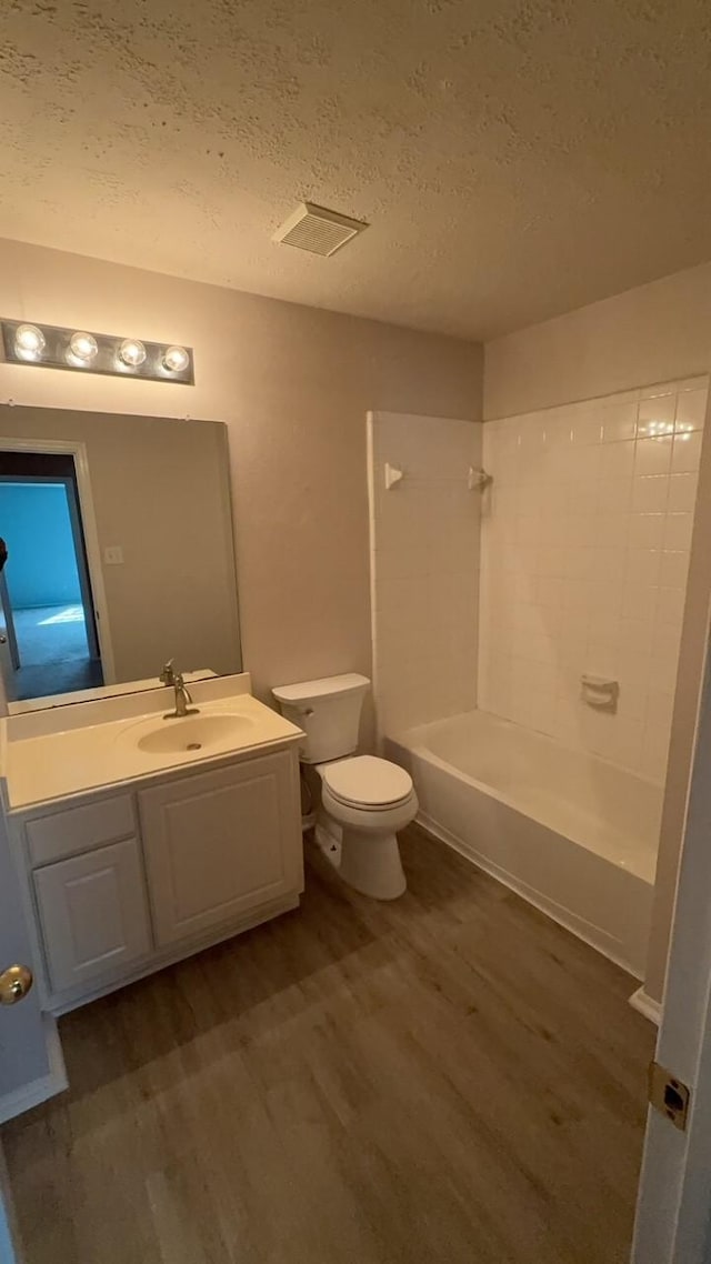 full bathroom with toilet, bathing tub / shower combination, a textured ceiling, vanity, and hardwood / wood-style flooring