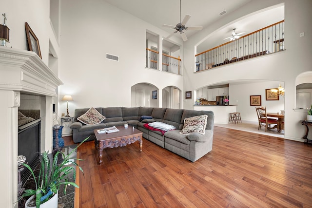 living room featuring ceiling fan with notable chandelier, a high end fireplace, and hardwood / wood-style floors