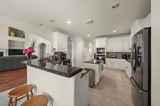 kitchen with sink, black appliances, kitchen peninsula, a kitchen island, and white cabinets