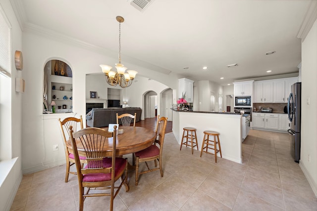 dining space featuring an inviting chandelier, light tile patterned floors, built in shelves, and crown molding