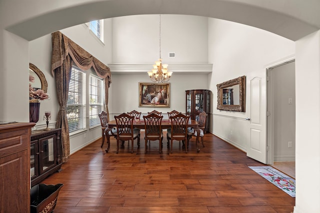 dining space with dark hardwood / wood-style floors, a chandelier, and a high ceiling