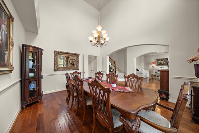 dining room with dark hardwood / wood-style flooring, a notable chandelier, and a towering ceiling