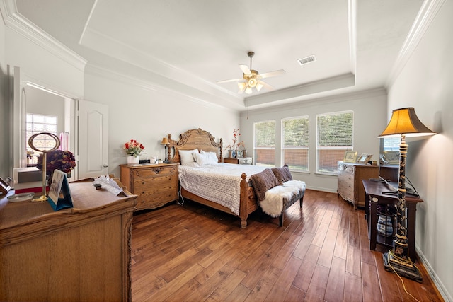 bedroom with hardwood / wood-style flooring, ceiling fan, ornamental molding, and a tray ceiling