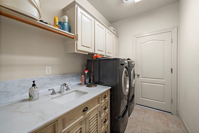 laundry room with cabinets, light tile patterned flooring, sink, and independent washer and dryer