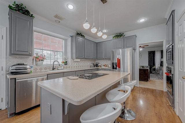 kitchen with a breakfast bar, sink, a center island, pendant lighting, and stainless steel appliances