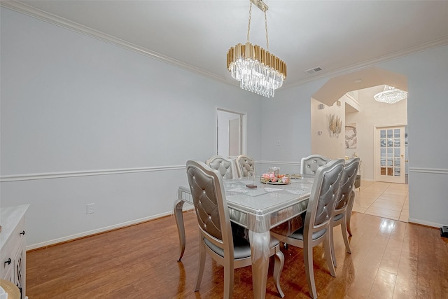 dining space with an inviting chandelier, crown molding, and light hardwood / wood-style flooring