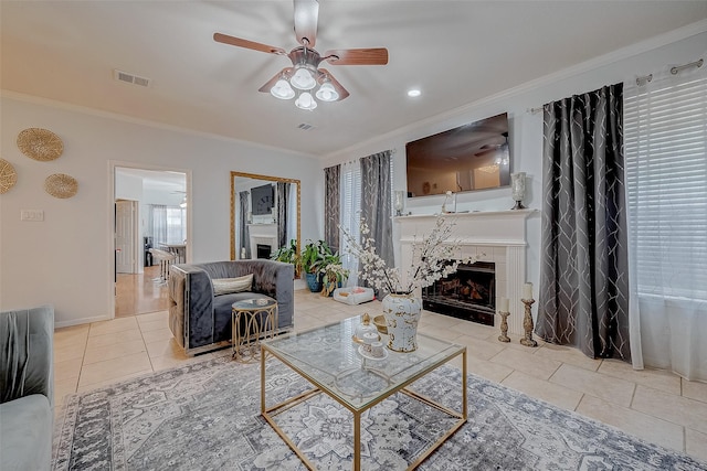 tiled living room featuring ceiling fan, ornamental molding, and a fireplace