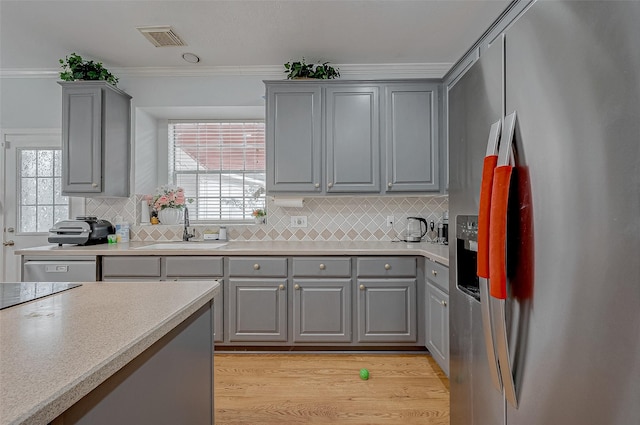 kitchen with crown molding, stainless steel fridge, sink, and gray cabinetry