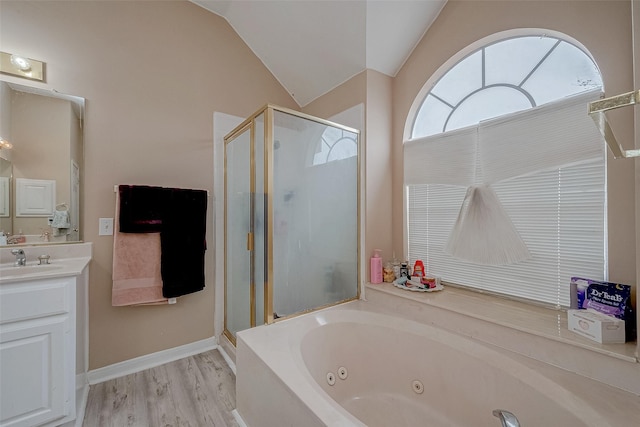 bathroom featuring vanity, independent shower and bath, vaulted ceiling, and hardwood / wood-style floors