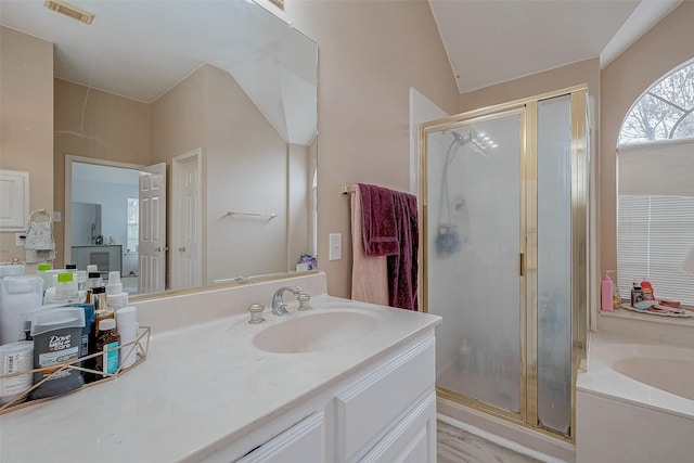 bathroom featuring independent shower and bath, vanity, and vaulted ceiling