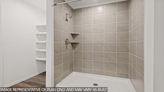 bathroom featuring wood-type flooring and a tile shower