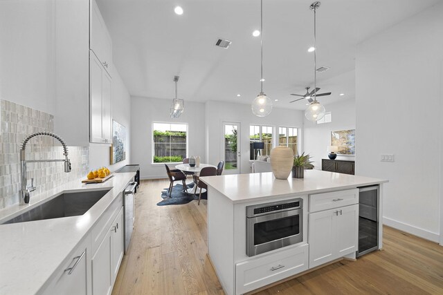 kitchen featuring visible vents, light wood-type flooring, a sink, wine cooler, and appliances with stainless steel finishes