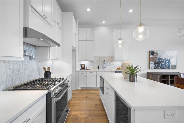 kitchen with stainless steel appliances, wine cooler, light wood-style floors, and white cabinetry