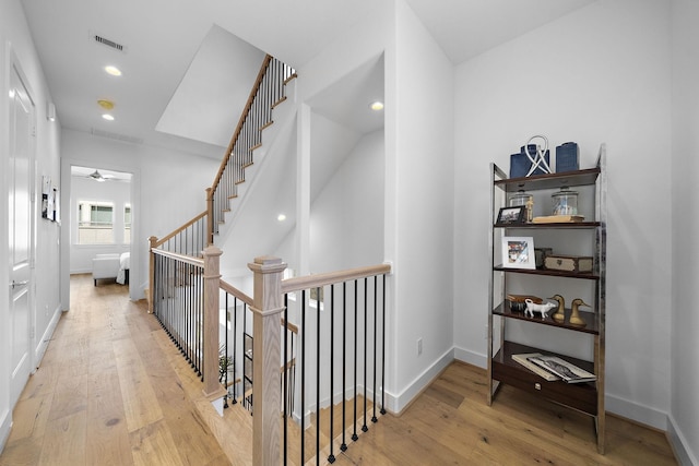 corridor with visible vents, an upstairs landing, baseboards, and hardwood / wood-style flooring