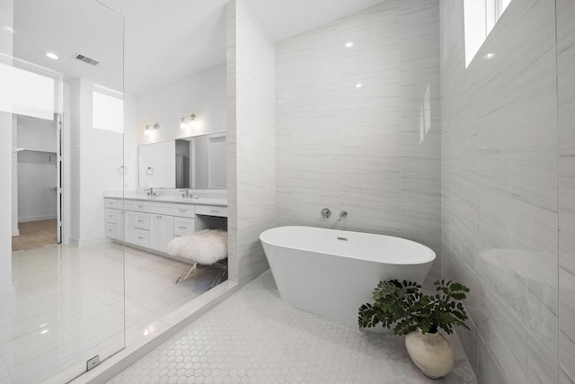 bathroom with vanity, visible vents, a freestanding tub, tile patterned floors, and tile walls