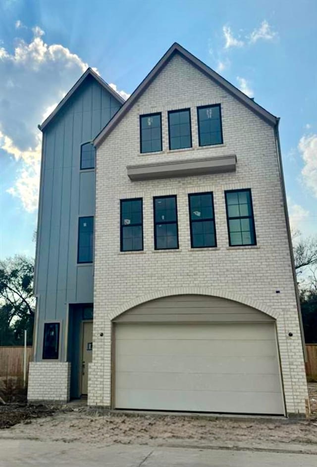 view of front of house with brick siding, board and batten siding, an attached garage, and driveway